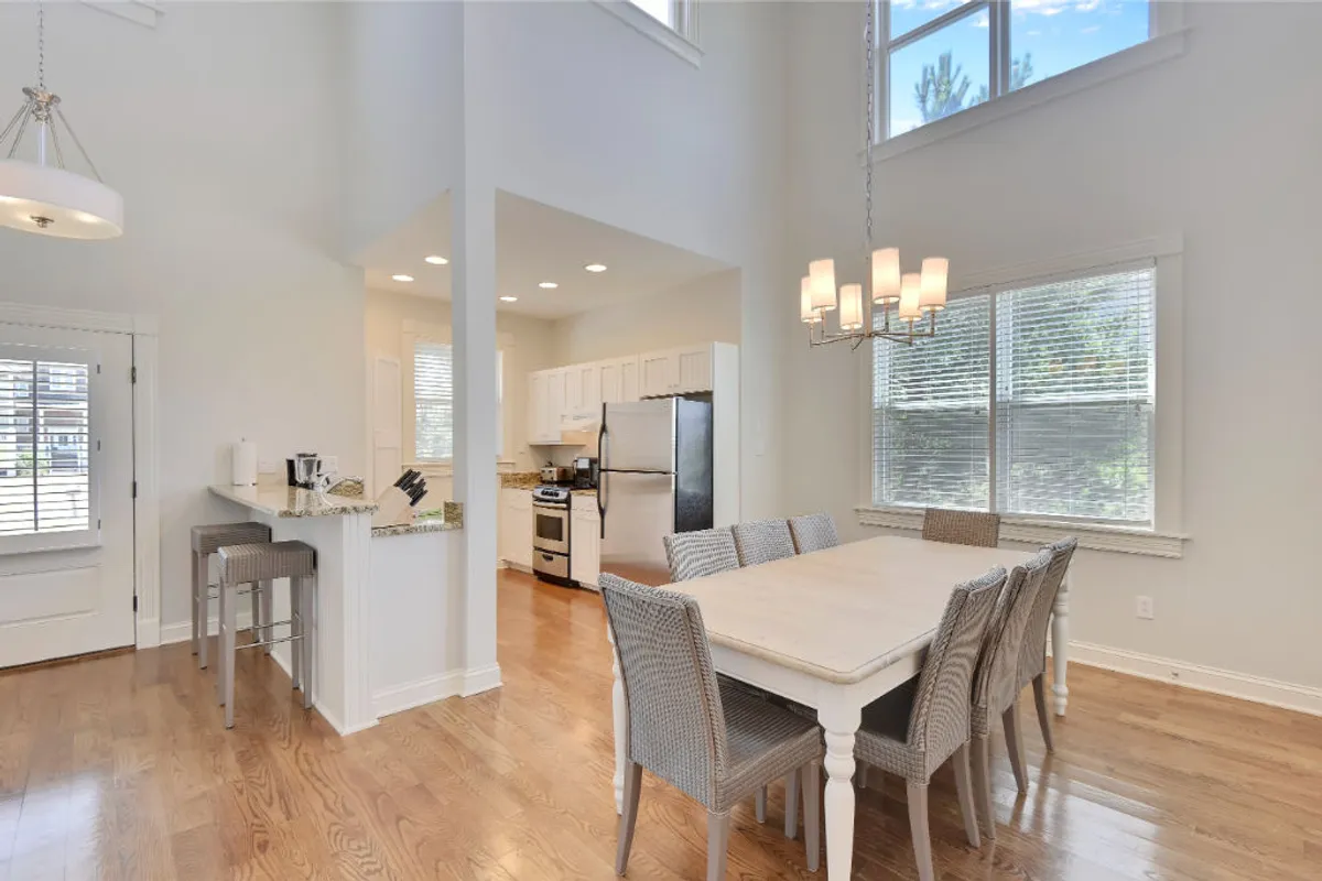 A stylish dining area seamlessly connected to an open kitchen, featuring a large dining table, kitchen island, and prominent windows letting in natural light. The setup suggests shared meals, conversation, and togetherness—perfect for holiday celebrations or casual dining with loved ones.