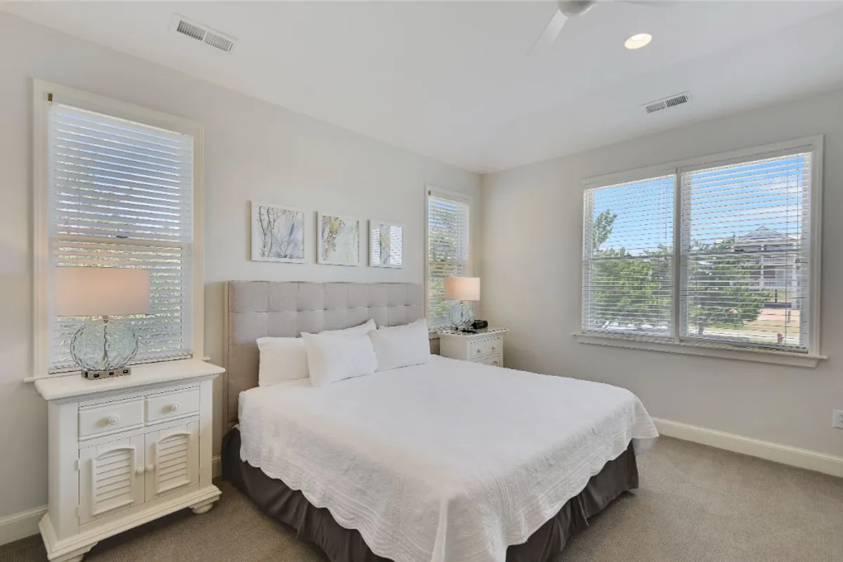 A second king bedroom, styled for serenity and comfort, featuring a plush bed, a well-placed nightstand, soothing artwork, and soft, natural light from the windows. The overall feel is one of peaceful retreat.
