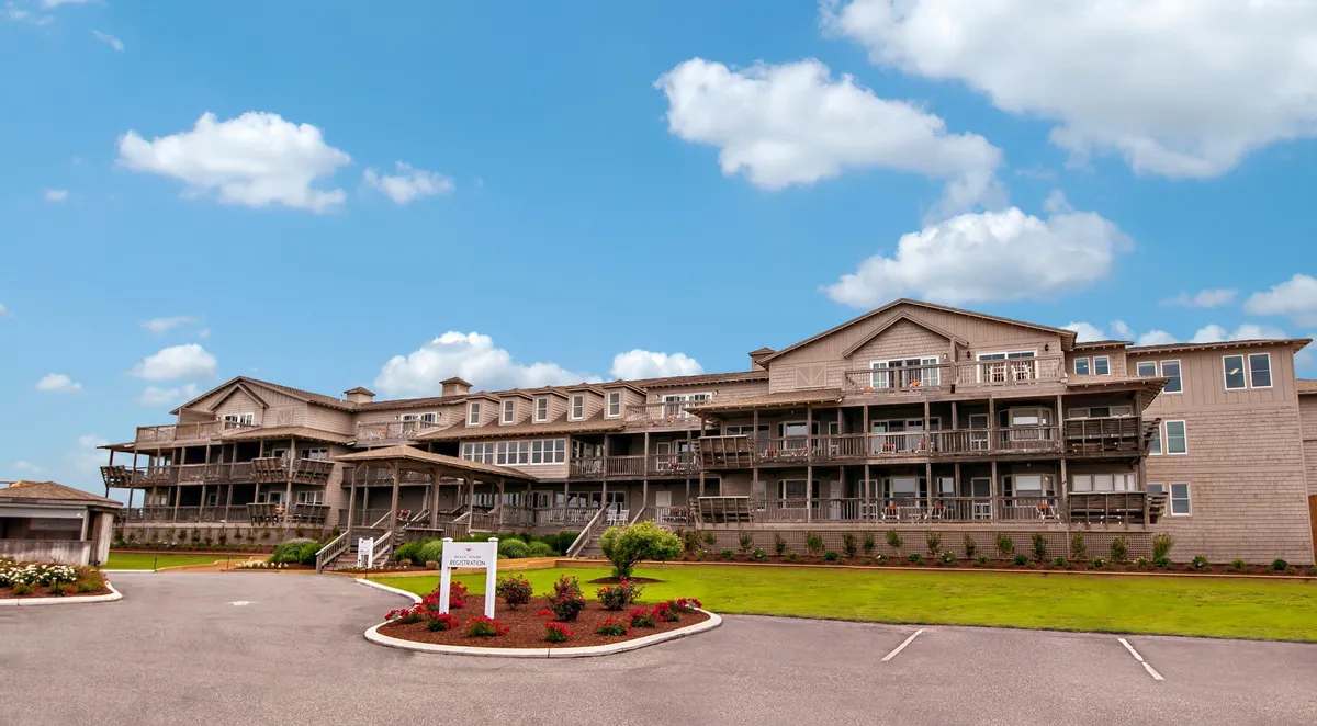 The image shows the resort's building facade with balconies and landscaped gardens. The peaceful grounds and welcoming atmosphere make it easy to imagine exploring the property with a pet, enjoying morning coffee on the balcony, or taking leisurely walks in the garden.